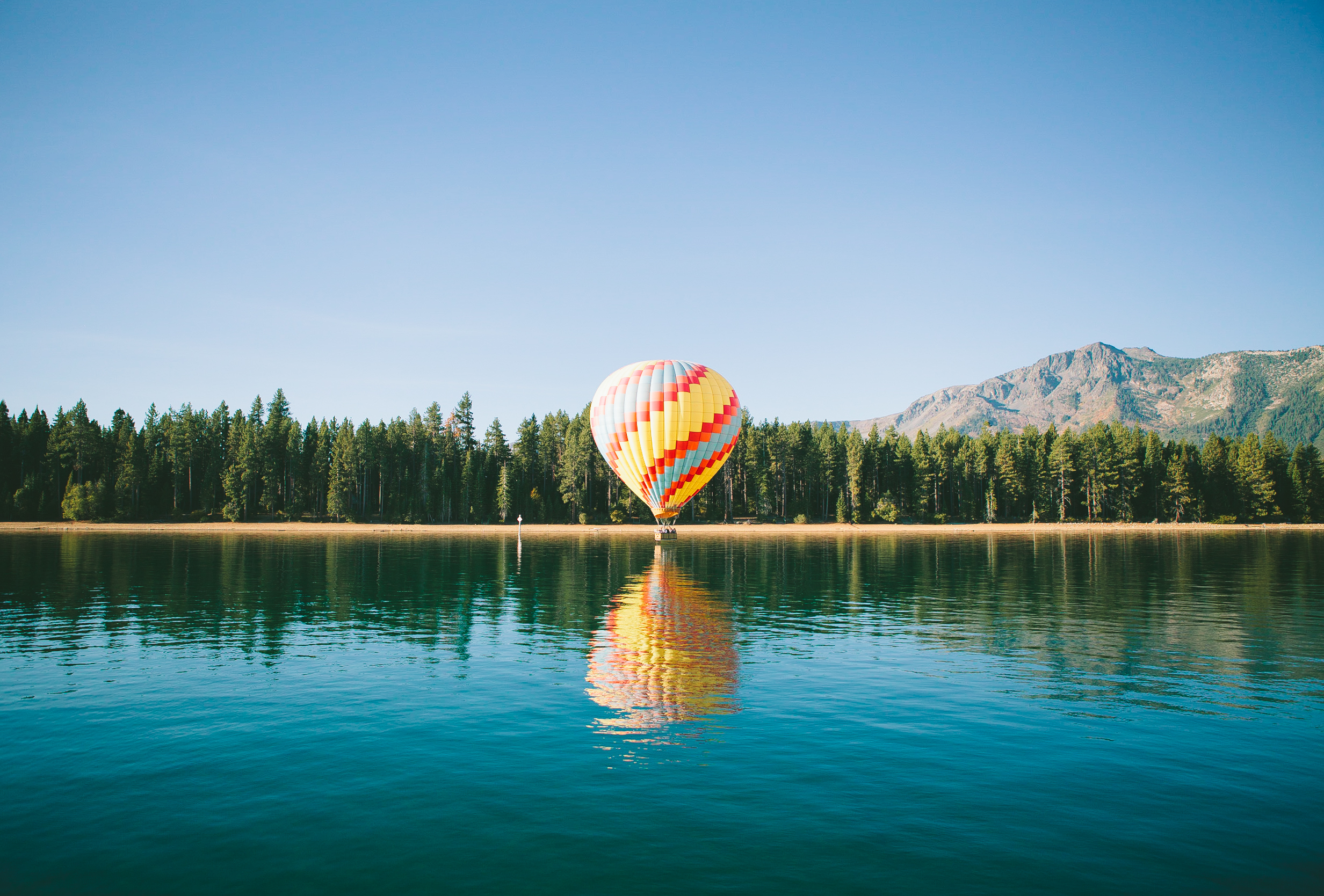 A hot-air balloon above the water and wooded south shore of Lake Tahoe